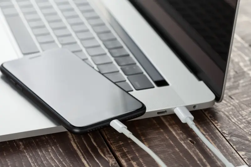A close-up of an iPhone plugged into a MacBook