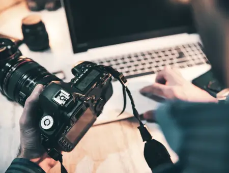 An image of a photographer at a desk with a camera and computer.