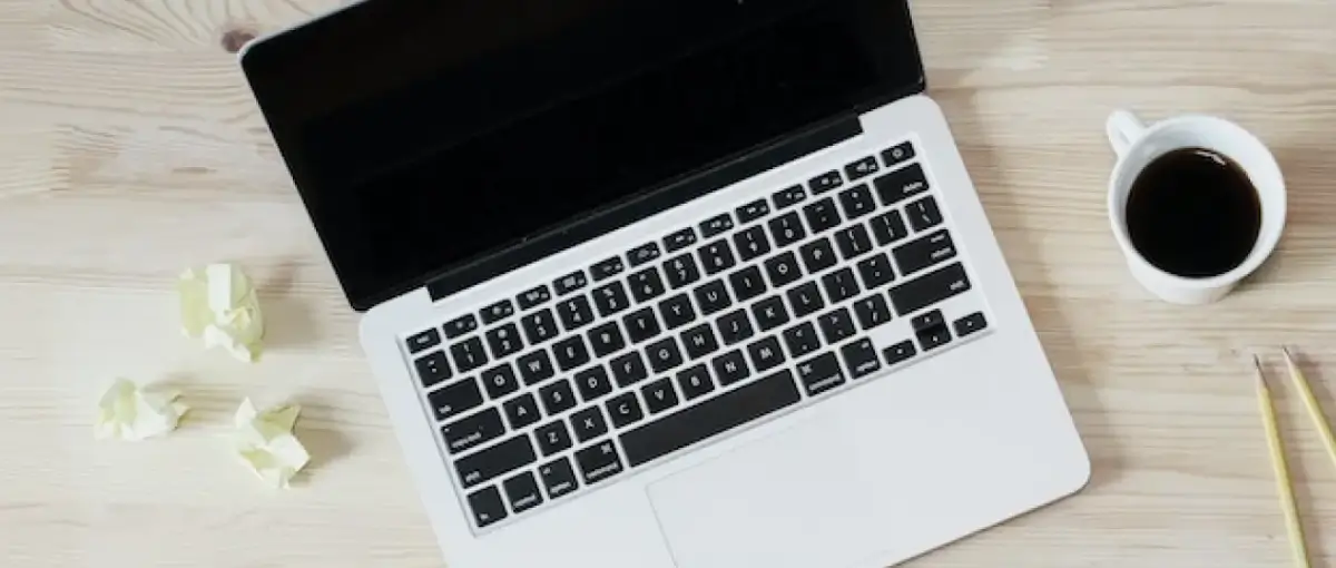 laptop on desk with coffee and a notepad