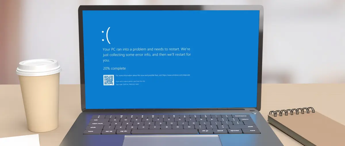 Windows laptop on desk with blue screen of death