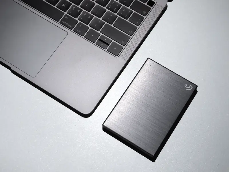 A laptop with an external drive next to it.