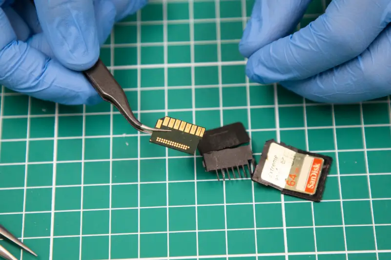 A photo of a data recovery engineer handling a damaged SanDisk memory card.