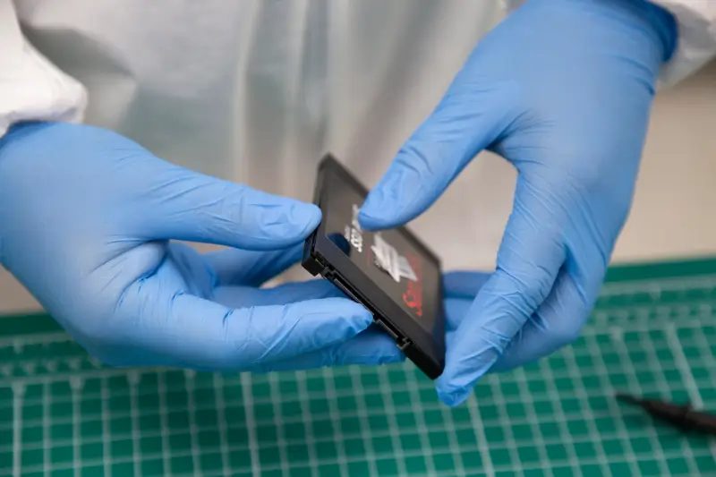 A photo of a data recovery engineer handling a SanDisk SSD in a certified laboratory.