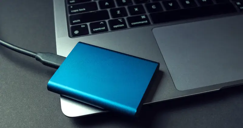 An external solid-state drive connected to a MacBook.